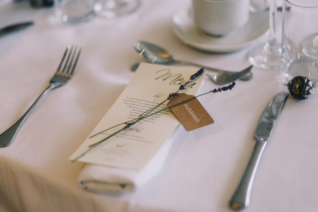 Tischdeko in der Gastronomie für eine Hochzeit mit einer weißen Tischdecke und einer Menükarte.