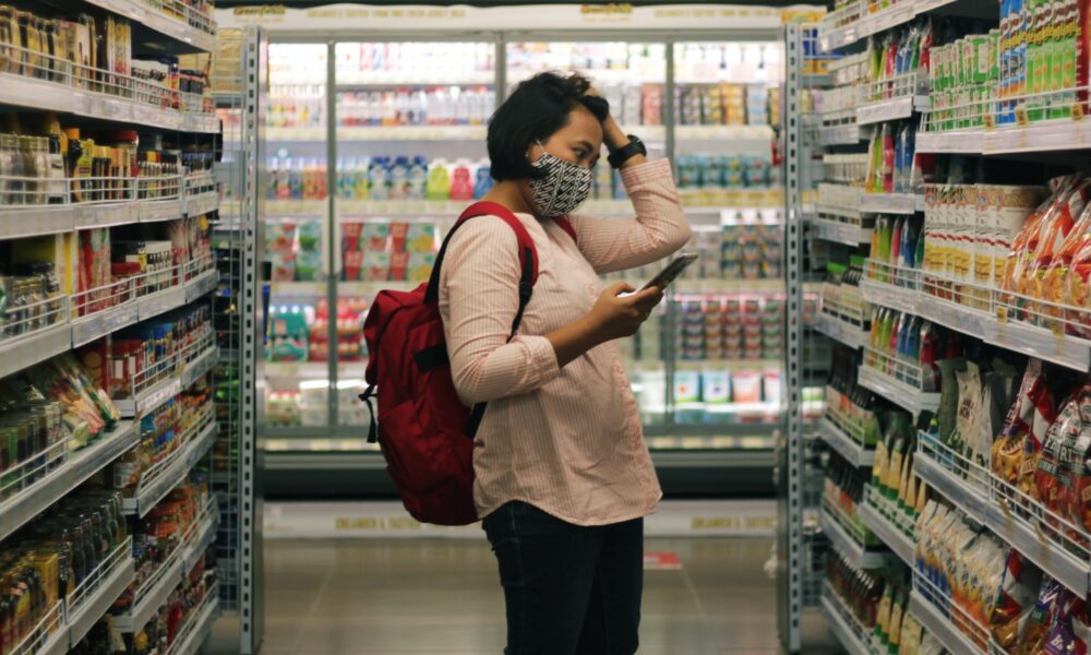 Eine Frau steht im Supermarkt und verzweifelt wegen dem Preisanstieg der Lebensmittel.
